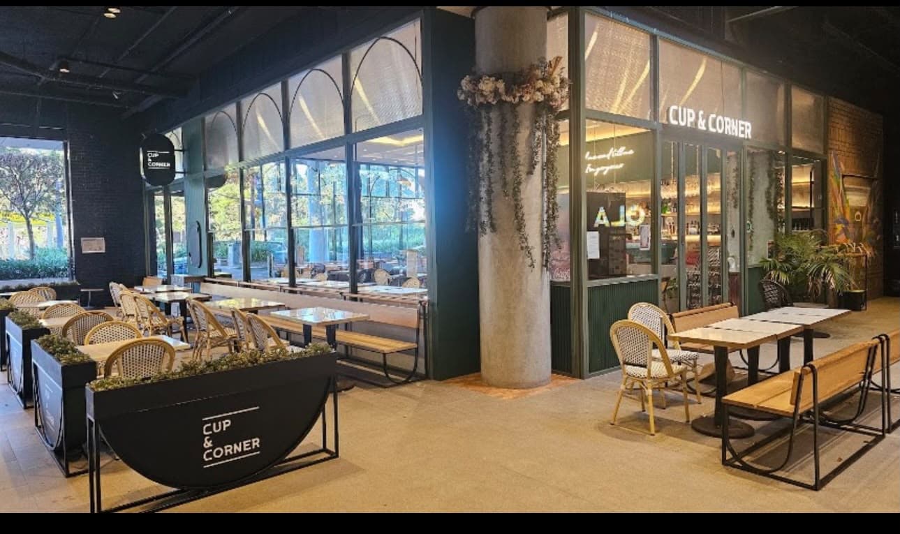 Warmly lit interior of Cup and Corner with timber tables and pendant lighting